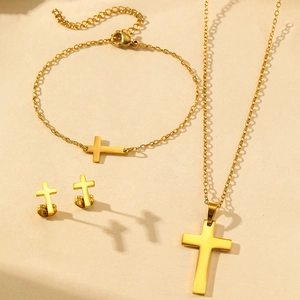 Golden stainless steel cross jewelry set with necklace, bracelet and earrings on beige