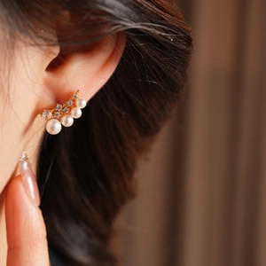 Detail of elegant 18k gold plated earring with white pearls and sparkling cubic zirconia