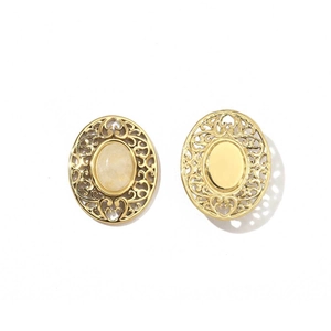 Detail of vintage gold hollowed-out earrings with an oval yellow gemstone on white background