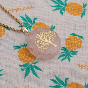Close-up of hexagonal pink stone pendant with golden tree of life on a twist chain