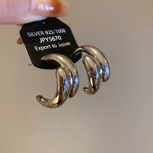 Macro shot of silver 925 three-layer C-shaped hoop earrings with polished finish