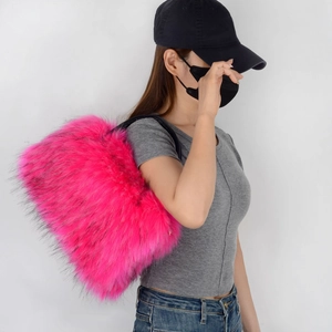Close-up of pink faux fur tote bag with black strap worn by model in casual style