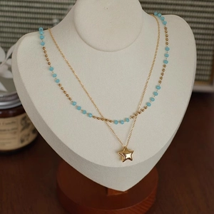 Détail du collier double rang avec pendentif étoile dorée et perles bleu ciel élégant