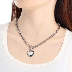 Detailed shot of silver heart pendant with thick chain and OT buckle on model neck