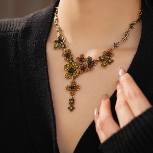 Gros plan d'un collier floral vintage avec gemmes vertes et ambre sur un mannequin