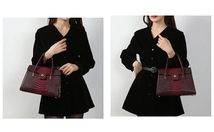 Close-up of deep red crocodile embossed leather handbag with golden lock detail