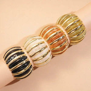 Detail of four acrylic stretch bracelets in black, white, amber, and olive with gold stripes