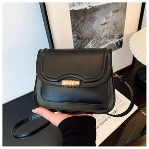 Détail d'un sac besace en cuir noir avec ferrures métalliques dans un décor chic