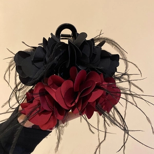 Macro detail of elegant burgundy fabric petals and soft feathers on a large hair claw clip