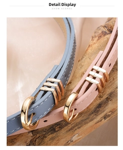 Close-up of thin leather belts in grey blue and pink with golden metal buckles