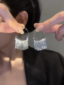 Close-up of silver tassel hoop earrings with sparkling metallic finish and long fringes