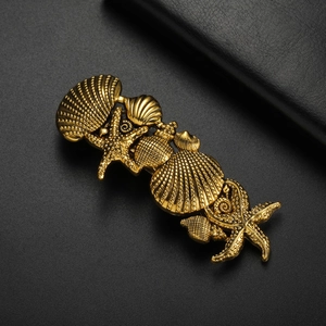 Close-up of vintage golden starfish and seashell hair clip with intricate textures