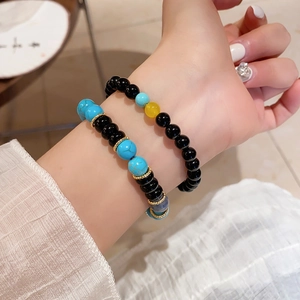 Detail of vintage beaded bracelets featuring turquoise and agate stones on a model's wrist