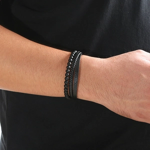 Detail of men's layered bracelet set with black volcanic stone beads and braided leather