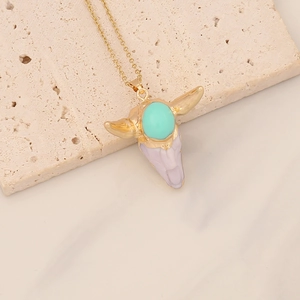 Detailed close-up of a bohemian bull head pendant with turquoise on a gold chain