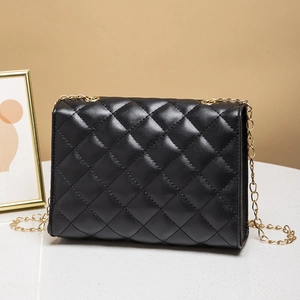 Elegant black quilted leather crossbody bag with a gold chain strap on marble