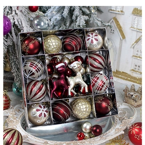 Detail of red and gold Christmas ball ornaments with reindeer figures in a festive gift box