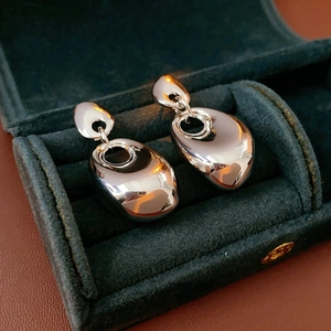 Detailed view of silver irregular oval metal earrings inside a green velvet jewelry box