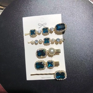 Macro view of five-piece vintage emerald rhinestone hair clips in deep blue and gold