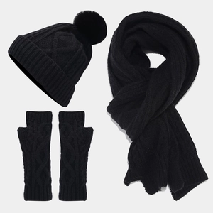 Detailed view of black cable knit winter set including pompom hat, scarf and fingerless gloves