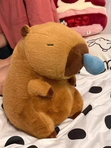 Nahaufnahme eines braunen Wasserschwein-Stofftiers mit blauem Blasendetail auf dem Bett