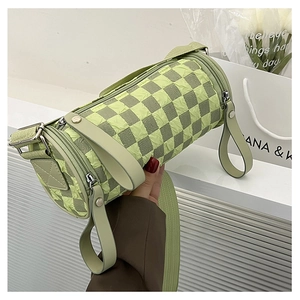Detail of green checkerboard cylinder bag with textured fabric and wide shoulder strap
