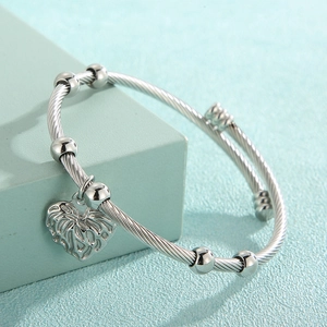 Detailed view of silver spiral wire bangle featuring heart charm and decorative beads