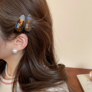 Détail de pinces à cheveux en acrylique écaille et bijoux en perles élégants sur un modèle