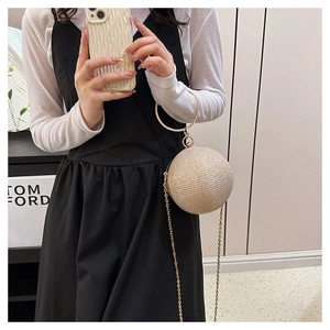 Detail of spherical gold evening bag with metallic ring handle and fine chain strap