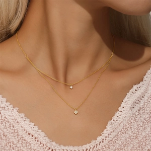 Detail of a double-layered 925 silver necklace with sparkling flower and clover pendants