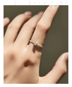 Détail d'une bague moissanite taille carrée avec anneau perlé en argent au doigt