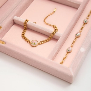 Detail of gold chain bracelets with floral charms in a pink velvet jewelry box