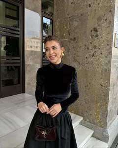 Détail d'une robe élégante en velours noir avec taille plissée et accessoires dorés