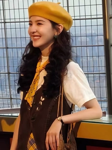 Detailed view of thick wool beret paired with a vintage vest and polka dot scarf