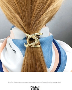 Detailed close-up of a golden U-shaped geometric hair tie on a minimalist ponytail holder