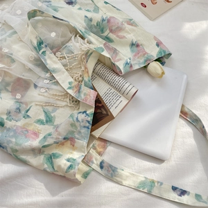 Close-up of floral linen tote bag featuring delicate white lace mesh and woven borders