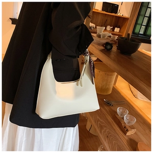 Detail view of white crescent shoulder bag with floral scarf handle and sleek leather finish