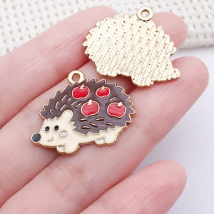 Détail d'un pendentif hérisson en émail avec motif pomme et dos doré texturé