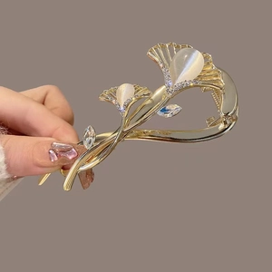 Detail der goldenen Ginkgoblatt-Haarklammer mit Katzenaugensteinen und Strasssteinen