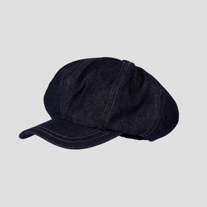 Détail de la casquette gavroche en denim bleu foncé avec des coutures orange contrastées