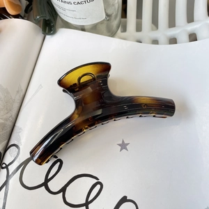 Close-up of large amber tortoiseshell hair claw clip on a stylish magazine background