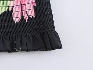 Close-up of smocking elastic design with floral print and ruffled hem on black fabric