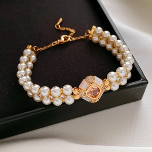 Détail macro du bracelet perles double rang avec gemme champagne dans un écrin noir