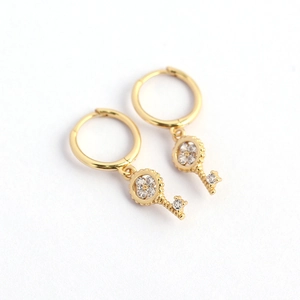 Gold s925 silver earrings with four-leaf clover key pendants and clear stones on white background