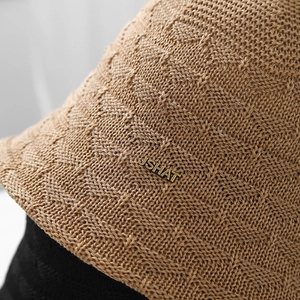 Detailed close-up of a khaki hollow breathable knitted bucket hat with gold metal label