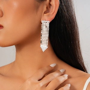 Boucles d'oreilles pendantes argentées sur un modèle avec une finition métallique brillante
