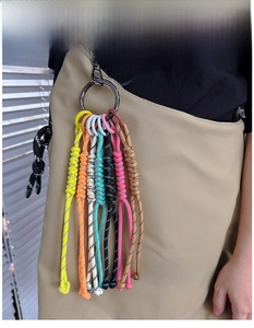 Close-up of vibrant woven rope keychains in 7 colors attached to a khaki handbag