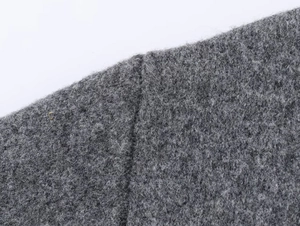 Macro view of grey knitted wool fabric showing dense fiber texture and vertical seam detail