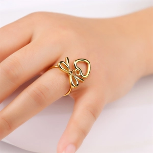 Elegant gold hollow heart and bow knot stainless steel ring worn on woman's finger