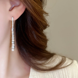 Gros plan de boucles d'oreilles pompon avec base argent, zircones et perles sur le mannequin